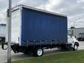 A 2006 Hino 268 truck with a boxy white cargo area covered in a blue tarpaulin and secured with straps on the sides