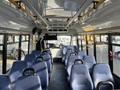 Interior view of a 2018 Chevrolet Express bus featuring blue seats arranged in rows with a high ceiling and overhead handrails