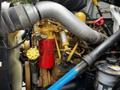 Engine components of a 2008 Ford F-750 showcasing a yellow oil filter a large silver pipe and various hoses and machinery parts