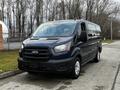 A blue 2020 Ford Transit van with a black grille and side windows parked on a street