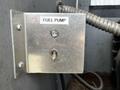 A metallic fuel pump switch with a labeled button and a small indicator light mounted on a metal panel