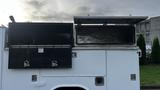 A white 2007 Ford F-550 with two open toolboxes on the side revealing empty storage compartments