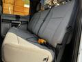 Interior view of a 2021 Ford F-550 showing a gray fabric bench seat with seat belts and a handheld device connected by a cable