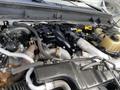 Close-up of the engine compartment of a 2015 Ford F-550 showing various mechanical components including hoses pipes and a coolant reservoir