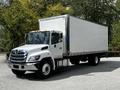 A 2020 Hino 338 truck with a white box cargo body and chrome detailing parked on a roadway