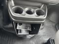 A cup holder with three openings and a small compartment containing several cards inside a 2022 GMC Savana
