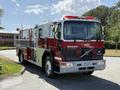 A red and white 1994 Volvo FE 42 fire truck with a ladder and emergency lights on top parked on a road