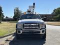 A 2016 Ford F-550 truck with a bucket lift attached on top and orange lights on the roof facing forward
