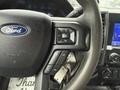 Close-up of the steering wheel of a 2020 Ford F-550 featuring the Ford logo and controls for volume and audio settings