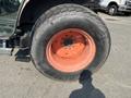 Close-up of a 2010 Kubota M6040 tractor tire with an orange rim and a rugged black tread pattern