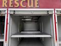 A compartment of a 2007 Ford F-550 rescue vehicle showing empty shelving and a retractable metal door
