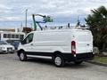 White 2023 Ford Transit van with roof racks and black accents parked on a concrete surface