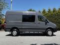 A 2017 Mercedes-Benz Sprinter van in grey parked on a paved surface with a high roof and large side windows