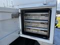 A storage compartment of a 2004 Freightliner M2 truck featuring three stacked metal drawers with labels attached
