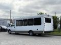 A white 2020 Chevrolet Express shuttle bus with large tinted windows and a high roof is parked at an angle showing its rear and side profile