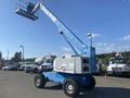 A blue 1997 Genie S-65 4X4 aerial lift with a raised basket and four wheels positioned on a pavement surface