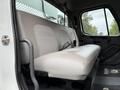 A two-person bench seat in a 2005 Freightliner M2 106 with a light-colored vinyl cover and seatbelt attachments