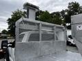 A 2011 Ford F-550 truck with a silver metal bed and diamond plate surface featuring a mesh enclosure and a tall exhaust stack