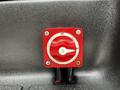 A red rotary switch with an off and on setting labeled with the number three, mounted on a textured gray surface