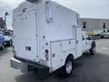A white 2015 Ford F-550 with a large white utility service body and various compartments visible on the side