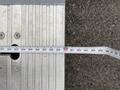 A measuring tape laid out across a metal surface showing various measurements and markings