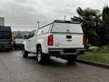 A white 2018 Chevrolet Colorado pickup truck with a cap on the bed parked at an angle showing the rear and side of the vehicle