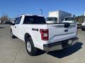 A white 2019 Ford F-150 truck with four-wheel drive parked showing its rear and side features including a truck bed and chrome accents