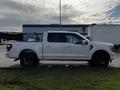 A white 2021 Ford F-150 pickup truck with a crew cab and black wheels parked on grass