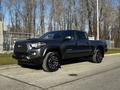 A 2021 Toyota Tacoma in black with a double cab and sporty design featuring a bold front grille and large alloy wheels