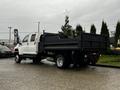 A 2005 GMC C5 Duramax truck with a flatbed design parked on a wet surface showcasing its large rear wheels and robust body