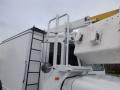 A white 2002 International 4700 bucket truck with a raised boom and a ladder on the side