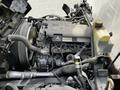 A 2015 Mitsubishi Fuso FE engine viewed from above with various components including hoses and a coolant reservoir visible