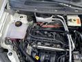 Engine compartment of a 2013 Ford Transit Connect showing the engine, hoses, and fluid reservoirs