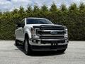 A 2020 Ford F-350 Super Duty with a white exterior and chrome detailing features a prominent front grille and large headlights
