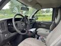 The interior of a 2014 GMC Savana featuring a steering wheel dashboard and front seats with items on the center console