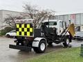 A 2016 Freightliner 108SD with a plow attached and a checkered reflective rear panel is parked with its back facing the viewer