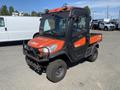 A 2018 Kubota ATV with a bright orange and gray exterior featuring a cabin, protective grille, and rugged tires