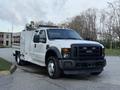 A white 2008 Ford F-450 truck with a flatbed and utility body featuring a tool compartment and roof-mounted lights