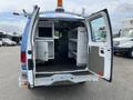 A blue 2009 Ford Econoline van with open rear doors revealing shelving and equipment storage inside