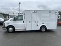 A white 2016 Chevrolet Express van with a boxy-shaped body and side doors designed for utility and transport