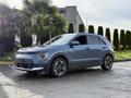 A 2023 Kia Niro EV in blue with modern headlights and black accents parked diagonally showcasing its sleek design and alloy wheels