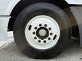 Close-up of a large black tire on a white wheel with multiple bolts, featuring the Bridgestone logo and visible tread pattern