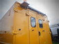 A yellow 2008 Freightliner MT45 Chassis with two side windows and a large rear door features a light bar and a traffic cone on the roof