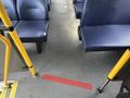 Interior view of a bus showing blue padded seats and a red strip on the floor indicating the area for standing passengers