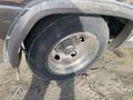 A close-up view of a wheel from a 1987 Chevrolet Fleetwood Pace Arrow showcasing a shiny alloy rim and a worn tire