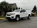 A white 2018 Chevrolet Colorado pickup truck with a fitted canopy parked on a road