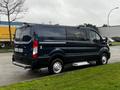 A 2020 Ford Transit van in dark blue parked with a side view showcasing its sliding door and wheels