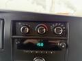 Dashboard controls of a 2014 GMC Savana showing temperature dials a digital clock and audio settings