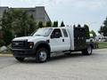 A white 2008 Ford F-450 SD truck with a flatbed and a black tool compartment on the side