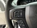 Close-up of the steering wheel controls of a 2018 Ford F-150 featuring buttons for navigation settings and cruise control
